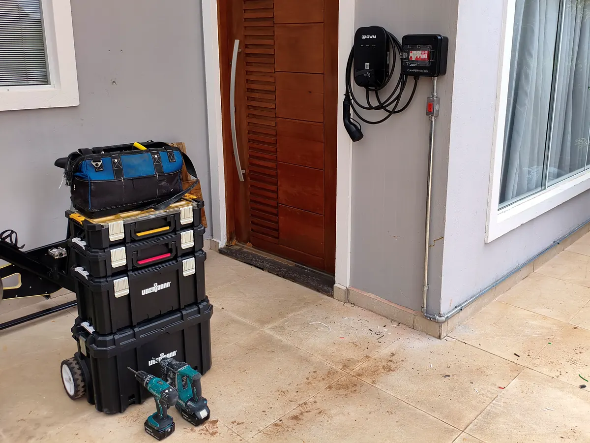 Maletas de ferramentas e furadeira do eletricista na entrada da residência atendida